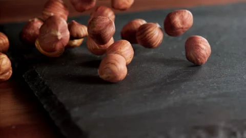 A bunch of hazelnuts falling on a slate table Stock Footage 152383765