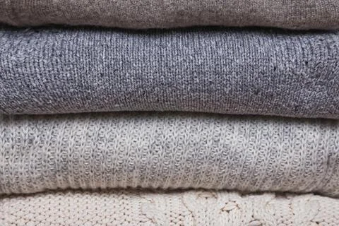 Bunch of knitted warm sweaters, different knitting patterns folded in stack Stock Photos