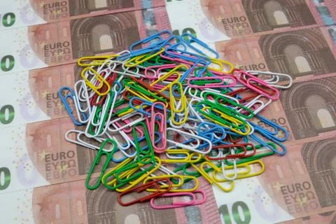 A bunch of multi-colored paper clips lies on 10 Euro banknotes. Close up Stock Photos