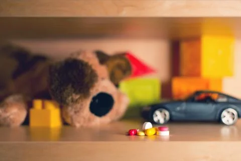 A bunch of multi-colored pills on the background of blurry children's toys Stock Photos