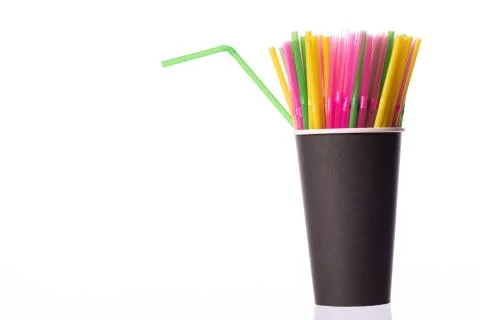 Bunch of multi colored plastic straws in black disposable biodegradable cup Stock Photos