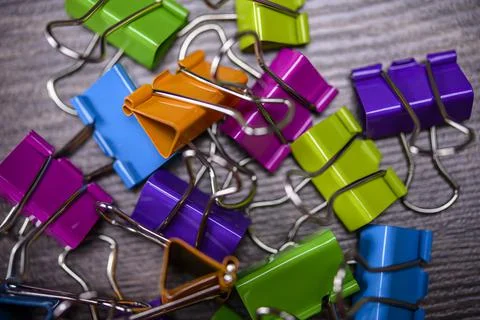 Bunch of multicolored binder clips on table Stock Photos