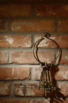 Bunch of old brass skeleton keys hanging on a brick wall 스톡 사진
