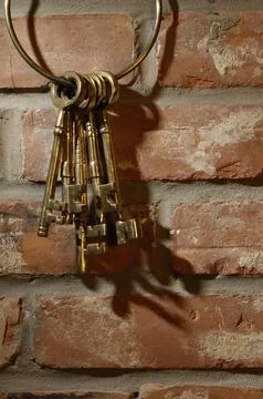 Bunch of old brass skeleton keys hanging on a brick wall 스톡 사진