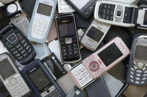 Bunch of old used outdated mobile phones and batteries. Recycling electronics Stock Photos