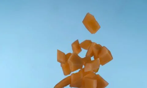 A bunch of orange melon cubes are suspended in mid-air against Stock Photos