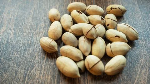 A bunch of pecans rests on a smooth, uniform background, showcasing their r.. Stock Photos