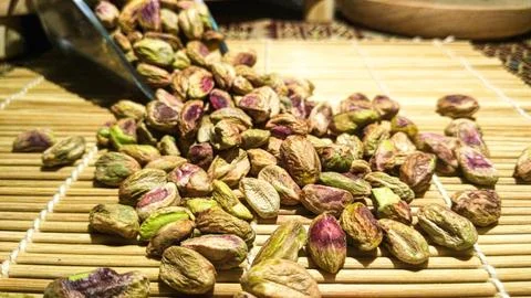 Bunch of pistachio nuts kernel scattered from a scoop on top of sushi mat w.. Stock Photos