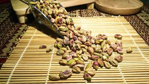 Bunch of pistachio nuts kernel scattered from a scoop on top of sushi mat w.. Stock Photos