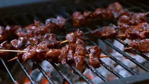 Bunch of pork sate being turned and roasted on a hot bbq Stock Footage 75249772