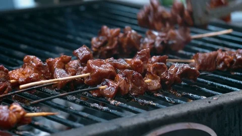 Bunch of pork sate being turned and roasted on a hot bbq Stock Footage 75249856