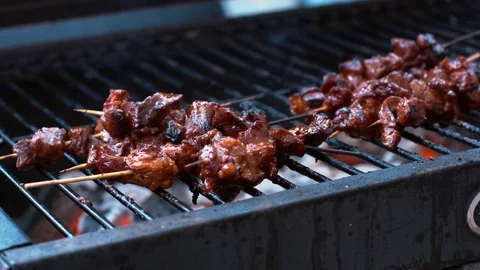 Bunch of pork sate being turned and roasted on a hot bbq Stock Footage 75249926