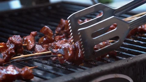 Bunch of pork sate being turned and roasted on a hot bbq Stock Footage 75250067