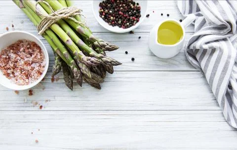 Bunch of raw asparagus stems with different spices Stock Photos