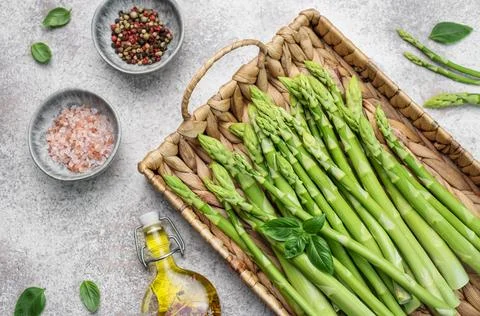 Bunch of raw asparagus stems with different spices Stock Photos