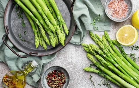 Bunch of raw asparagus stems with different spices Foto stock