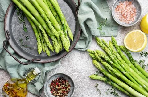 Bunch of raw asparagus stems with different spices Stock Photos