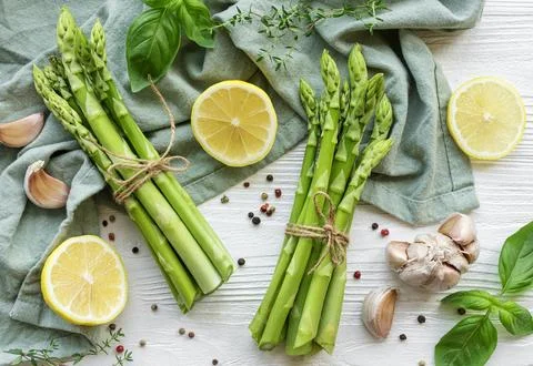 Bunch of raw asparagus stems with different spices Stock Photos