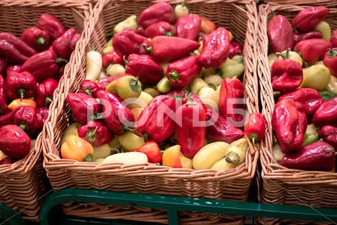 Bunch of red and yellow paprika peppers in wicker boxes in supermarket Stock Photos