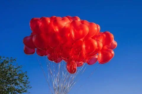 Bunch of red balloons in shape of a heart on background of blue sky Stock Photos