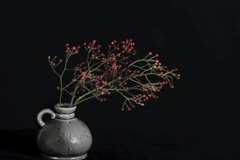 Bunch of red berries on the table in a grey vase. Stock Photos