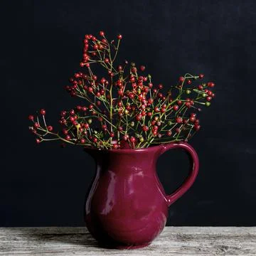 Bunch of red berries on the table in a red vase. Fotos Stock