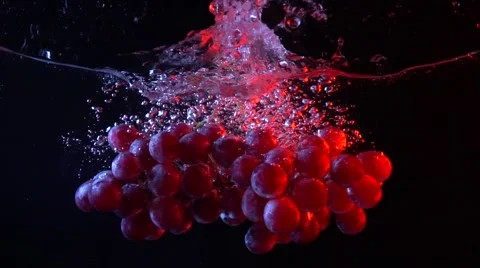 Bunch of red grapes falling into water with splashes super slow motion shot Stock Footage 61421387