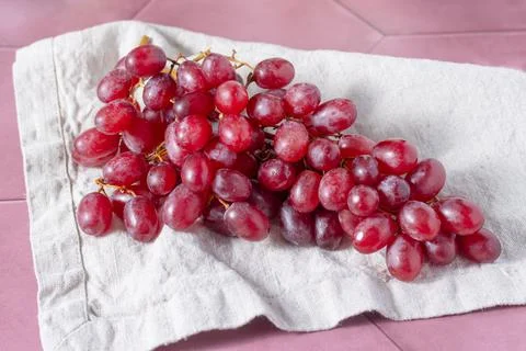 A bunch of red grapes is lying on a linen towel Stock Photos