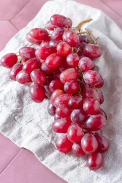 A bunch of red grapes is lying on a linen towel Stock Photos