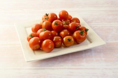 Bunch of red mini tomatoes on a square plate Stock Photos