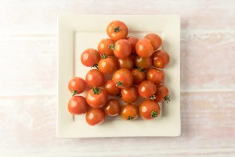 Bunch of red mini tomatoes on a square plate Stock Photos