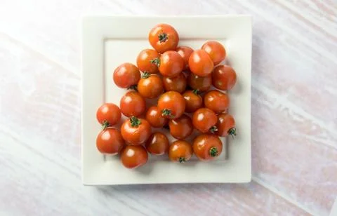 Bunch of red mini tomatoes on a square plate Stock Photos