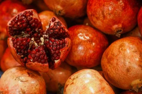 A bunch of red pomegranates with one of them cut in half Stock-Fotos