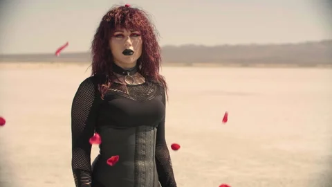 A bunch of red rose petals fly past gothic girl 스톡 동영상 293115258