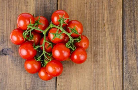 Bunch of red small round tomatoes on wooden background. Stock Photos