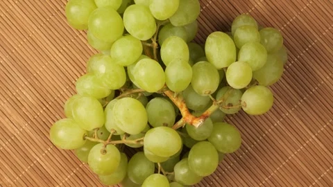 Bunch of ripe green grapes rotating on a bamboo mat Stock Footage 344604340