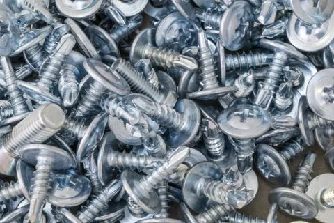 A bunch of screws lying on the table. There are a few screws. Stock Photos