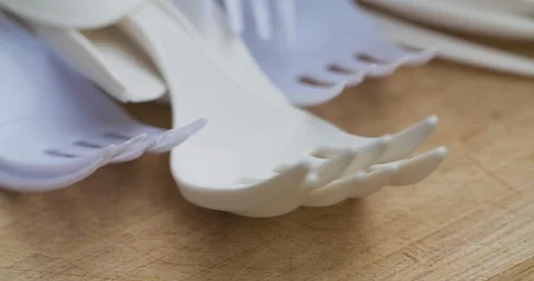 A bunch of single use plastic forks and spoons lying on a wood surface Stock Footage 111681368