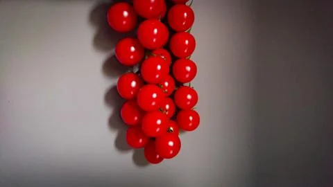 A Bunch Of Small Cherry Tomatoes Against A Gray Wall Background. Stylized Pho Stock Photos