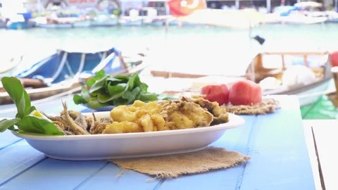 Bunch of small fried fish in plate. At restaurant with coast sea view in Foca Stock-Footage 80309558