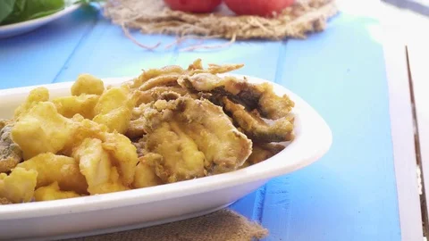 Bunch of small fried fish in plate. Close up macro view Greek style blue table Stock Footage 80310006