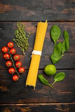 Bunch of spaghetti, raw pasta, on old dark wooden table background, top view  Stock Photos