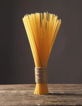 Bunch of spaghetti on a rustic wooden kitchen table, Italian food Stock Photos