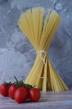 A bunch of tomatoes on the background of a bunch of spaghetti tied with a rop Stock Photos