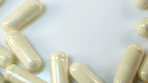 A bunch of transparent capsules with white powder inside are raked out of the fr Stock Footage 144643129