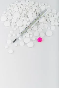 Bunch of white tablets with thermometer. Scattered pills. Stock Photos