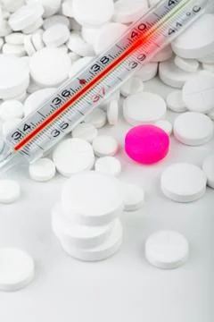 Bunch of white tablets with thermometer. Scattered pills. Stock Photos