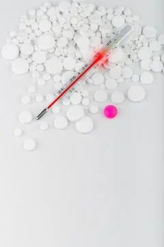 Bunch of white tablets with thermometer. Scattered pills. Stock Photos