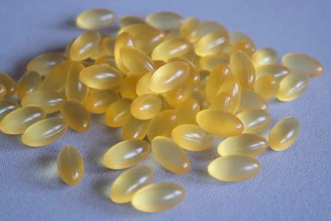 A bunch of yellow translucent vitamins capsules on a gray fabric Stock-Fotos