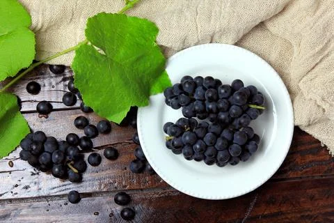 Bunches of fresh grapes, inside ceramic dish, on rustic wooden table Stock Photos